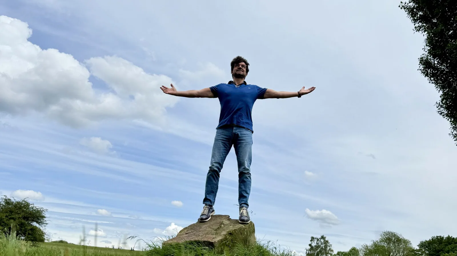 Justin Jernoiu mit weit ausgebreiteten Armen unter freiem Himmel