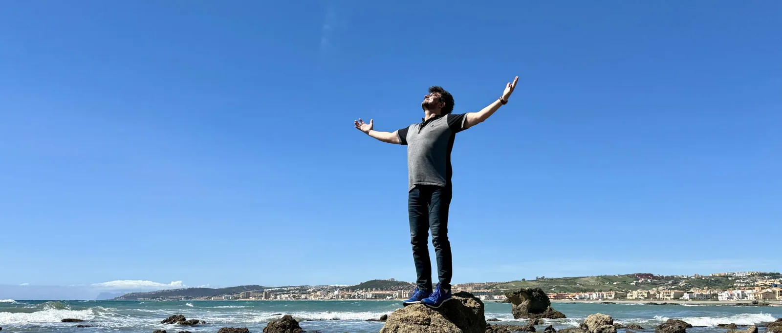 Weite Meeresküste mit einer Gestalt auf einem Felsen Weite Meeresküste mit einer Gestalt auf einem Felsen