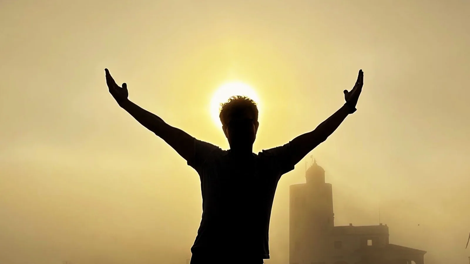 Silhouette mit erhobenen Armen vor der untergehenden Sonne Silhouette mit erhobenen Armen vor der untergehenden Sonne